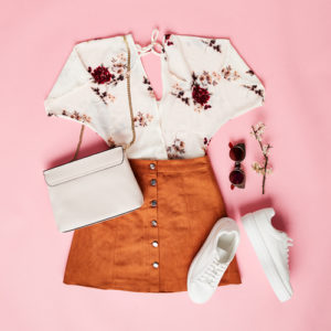 White top with red flowers, burnt orange skirt, White sneakers and purse 